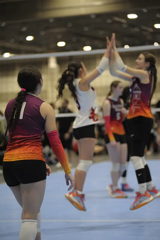 Teammates jump for a high-five at the net