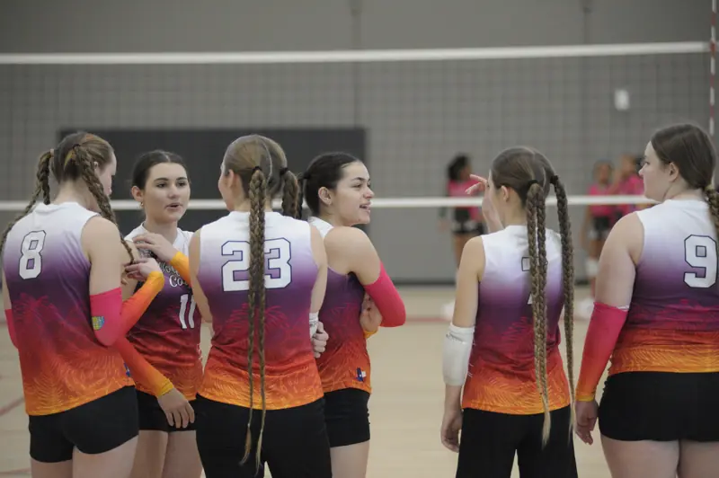 Players in orange-to-purple jerseys talk between points