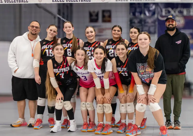 A team in black jerseys poses with two coaches